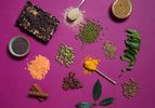 Overhead view of Indian pantry items arranged on a fuchsia surface.