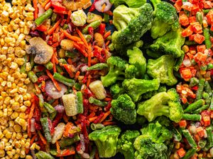 Assorted frozen vegetable pieces including broccoli corn and mixed vegetables arranged in bands