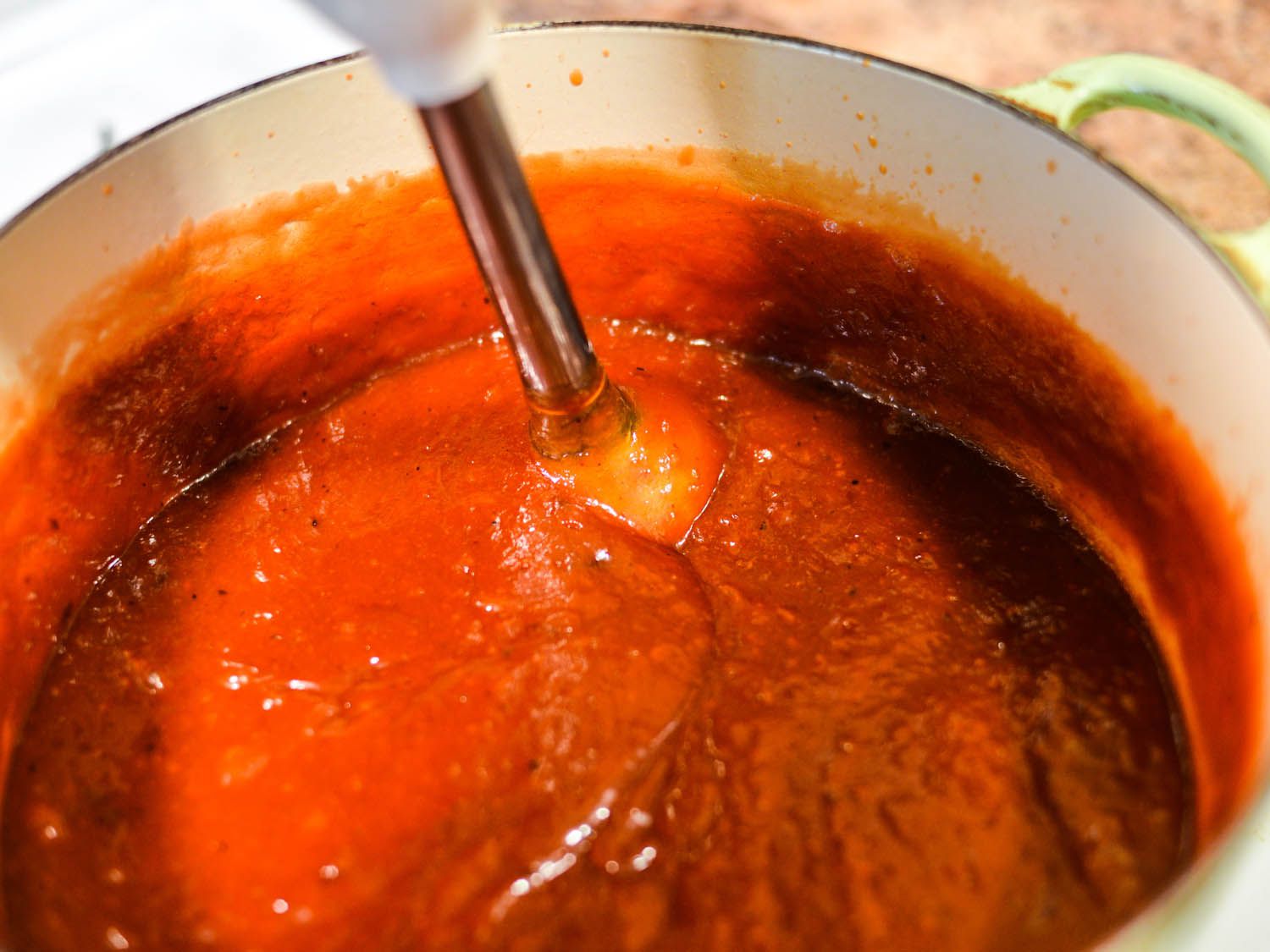 Immersion blender processing smooth barbecue sauce in a pot