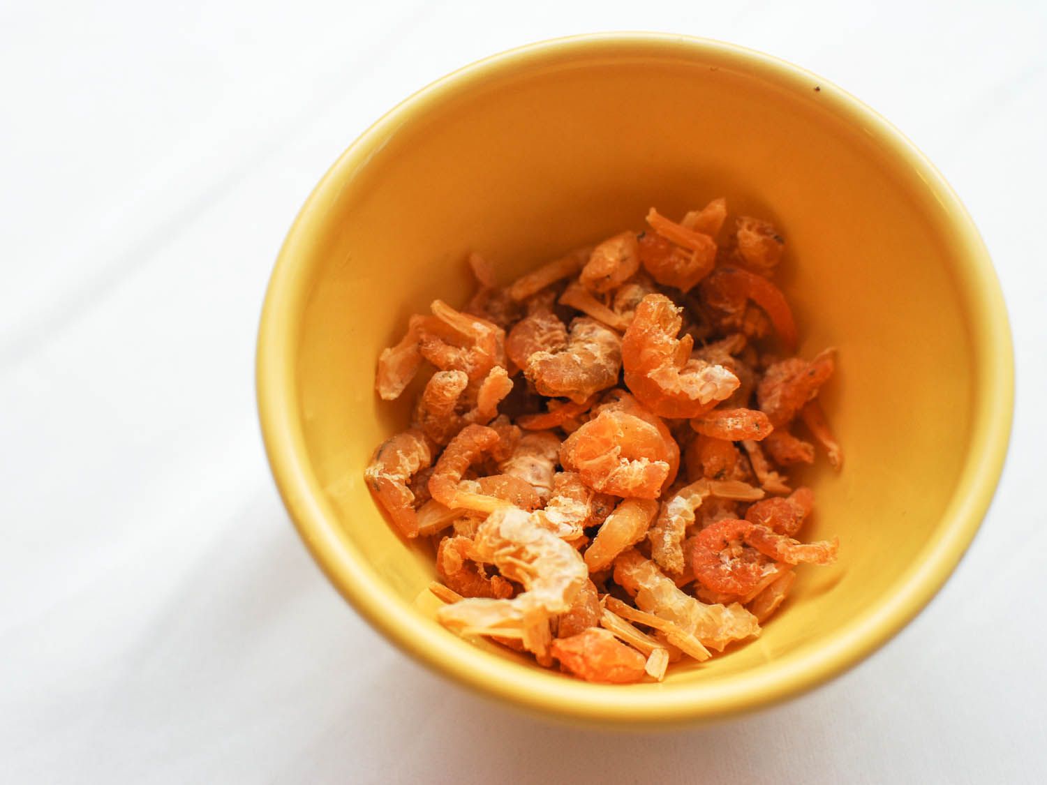 A yellow bowl with dried shrimp inside of it