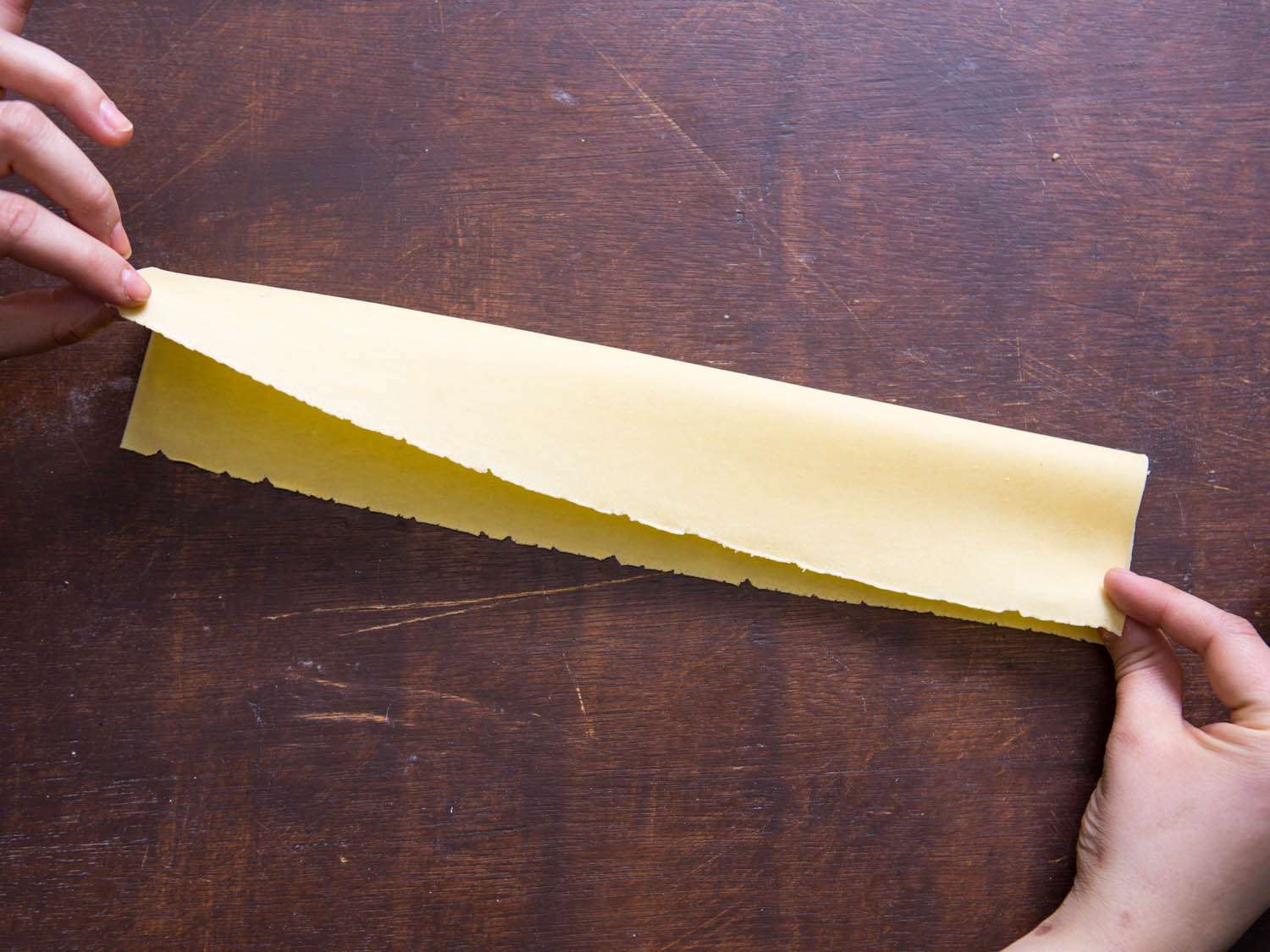 Folding a sheet of fresh pasta in half lengthwise.