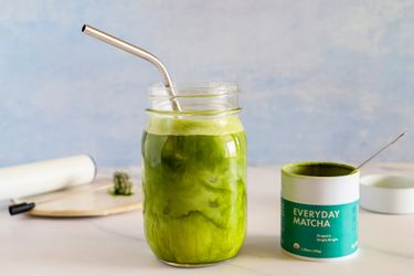 A glass of Rishi Tea Everyday Matcha next to the container