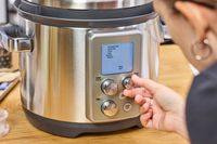 A person turns a dial on the front of the Breville the Fast Slow Pro