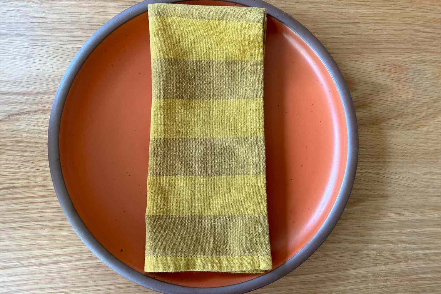 Yellow stripe cloth napkin on top of a orange plate
