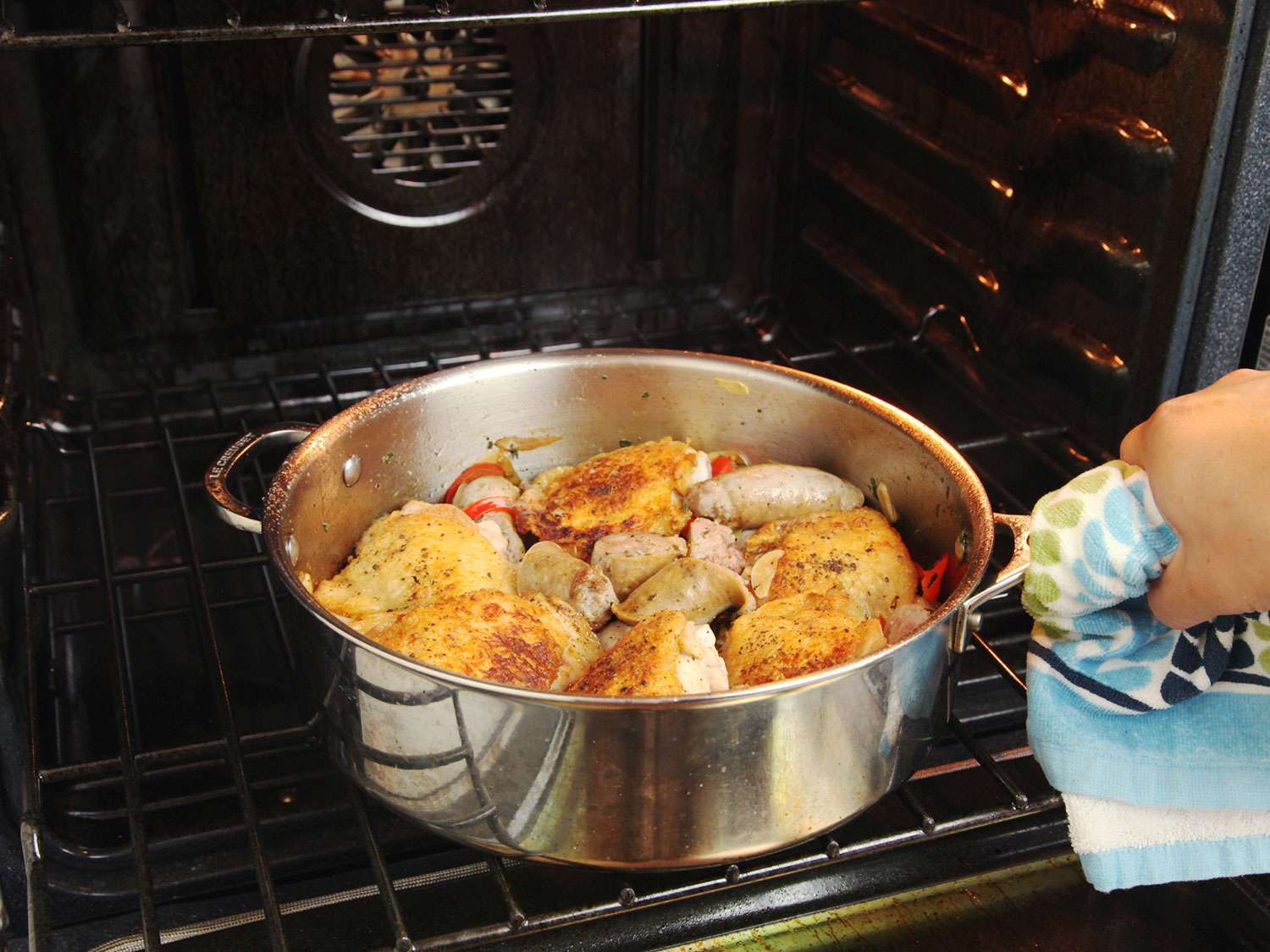 Transferring the pan containing chicken scarpariello to the oven. 