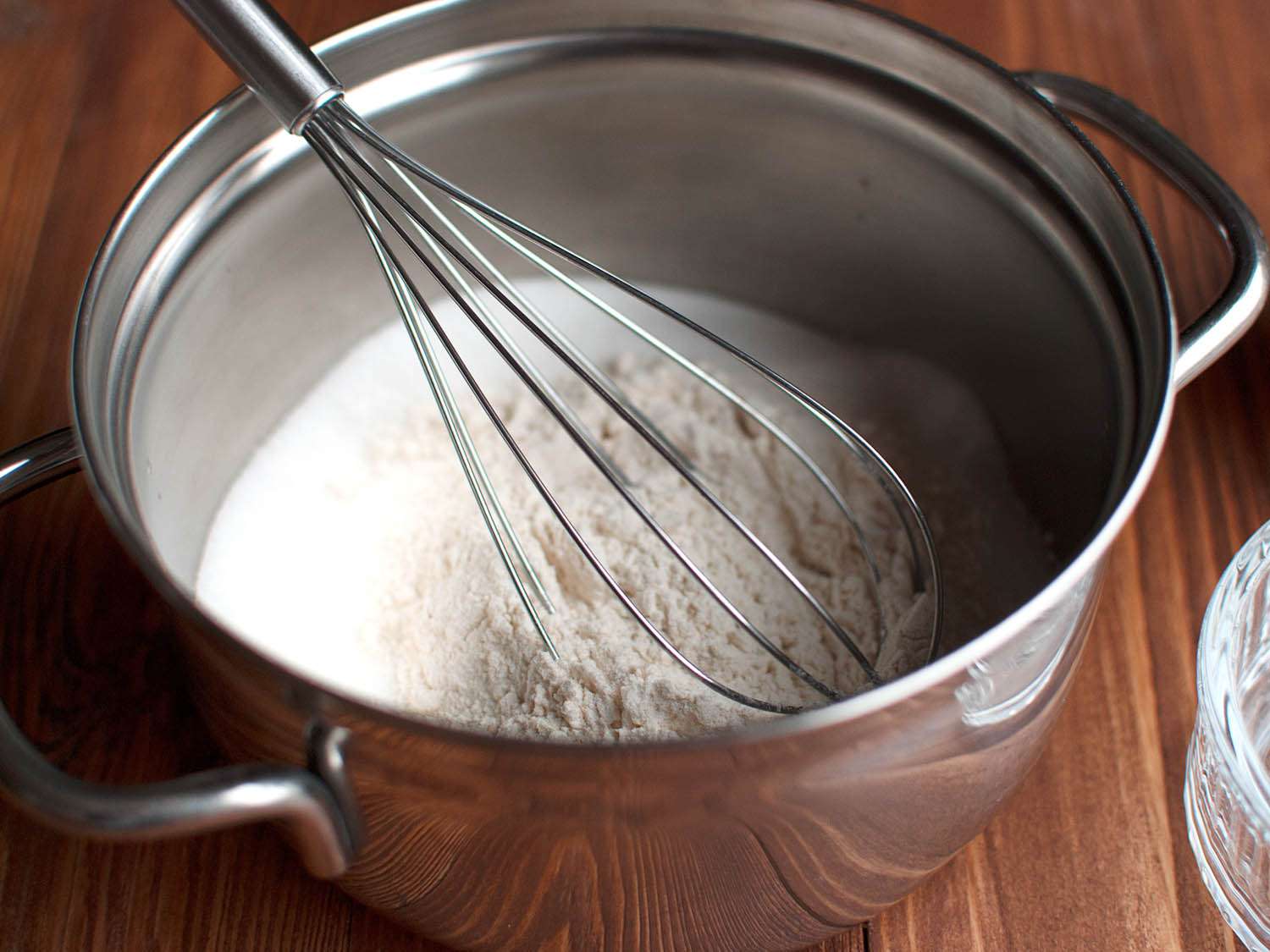 Flour and sugar being whisked together in a pot.