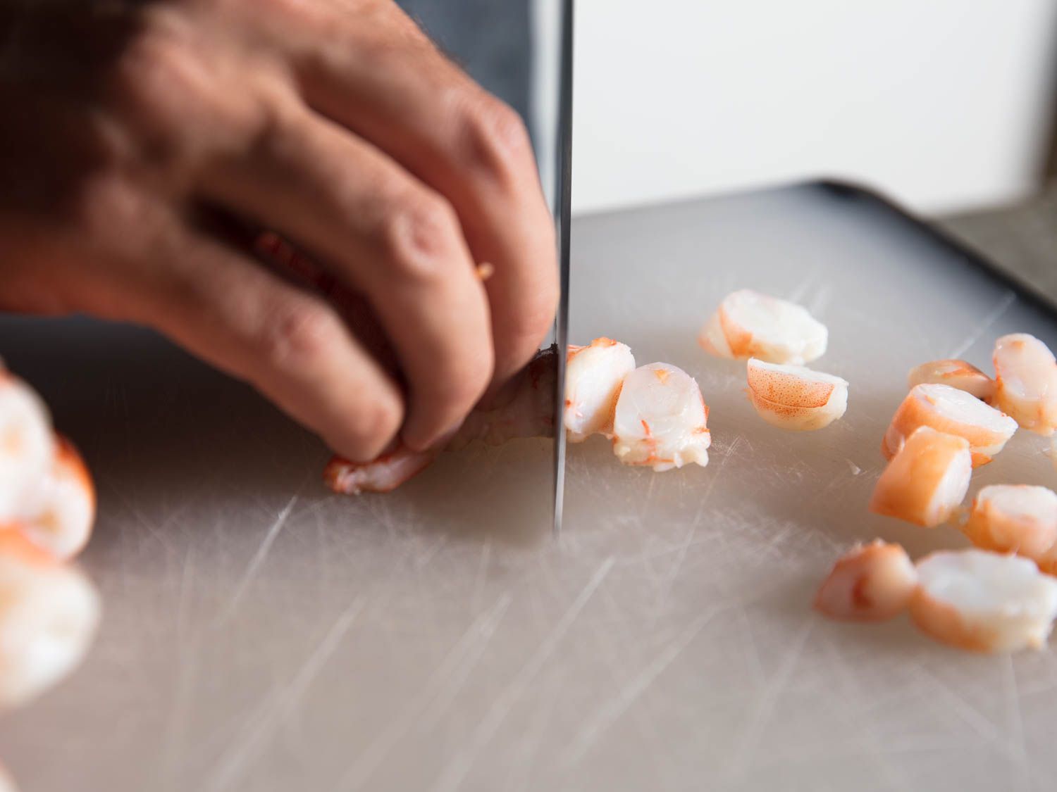 Cutting up poached shrimp for shrimp rolls