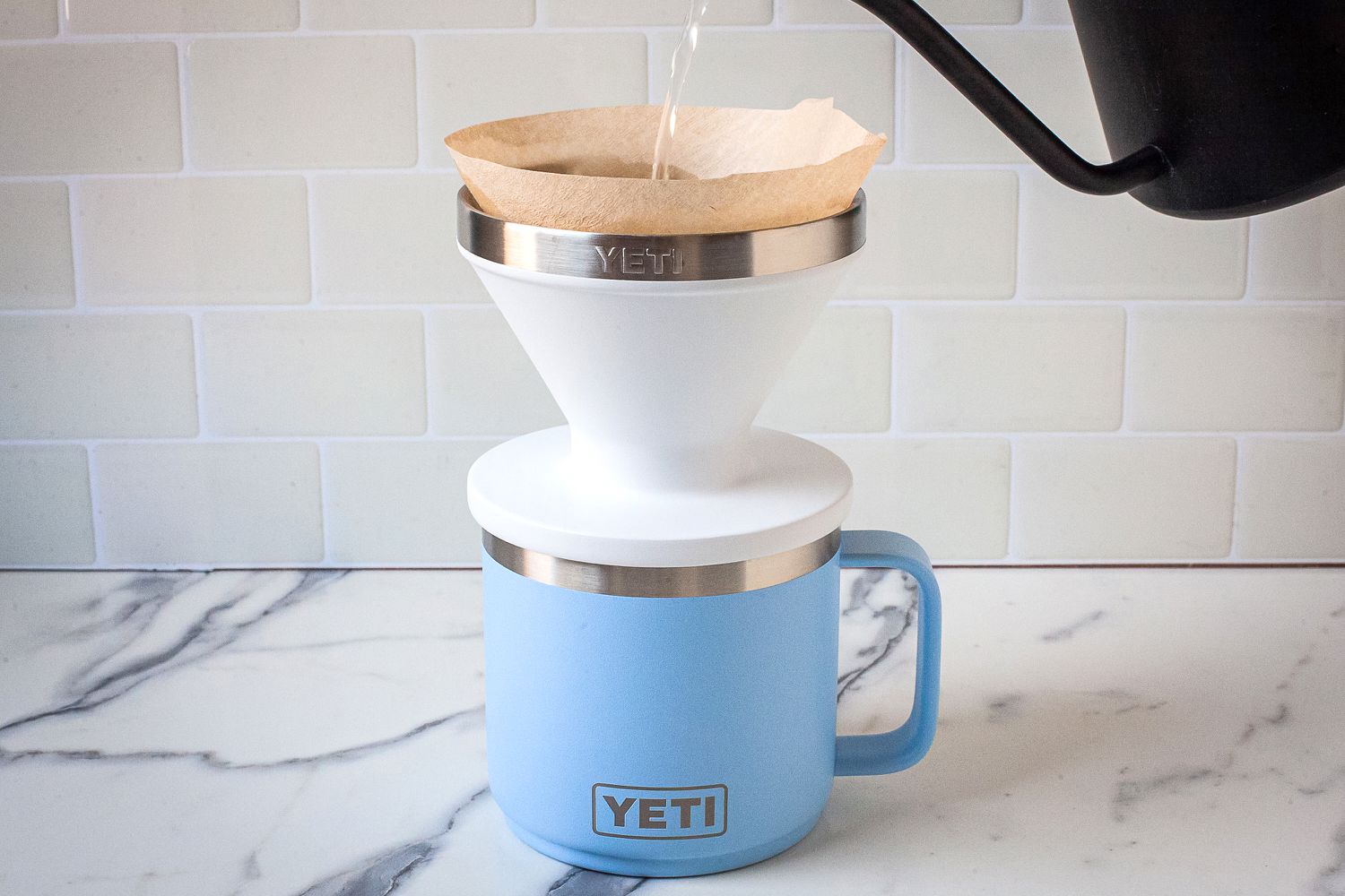 A kettle pouring water into the Yeti Rambler Pour-Over on top of a blue mug