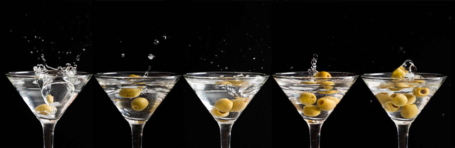 A series of martinis as olives drop in the glass and splash.