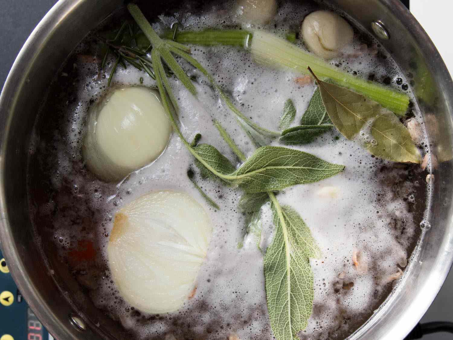 Overhead shot of dried beans simmering in a pot of water with aromatics.