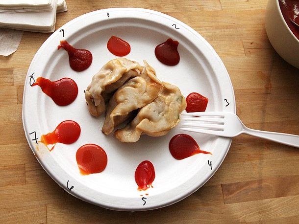 A plate with different dollops of sriracha for a taste test with pot stickers in the center 