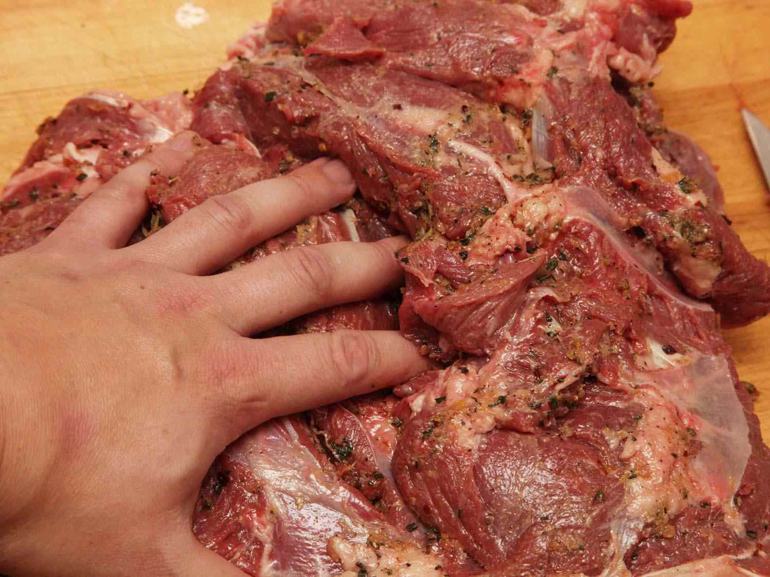 Author rubbing seasonings on the inner side of a butterflied leg of lamb.