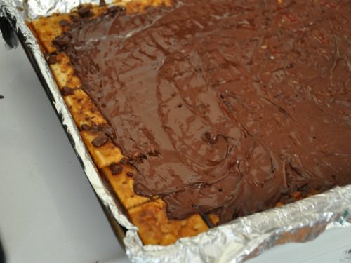 A foil-lined sheet pan of browned saltines now covered in melted chocolate.