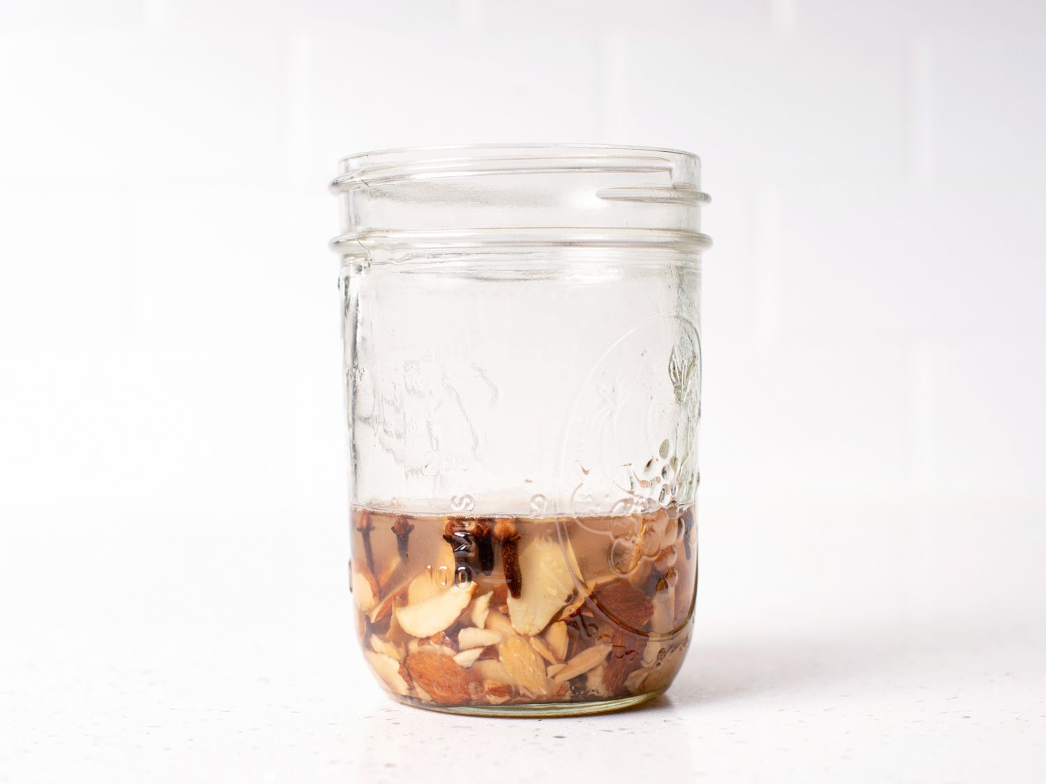 Toasted almonds, cloves, and rum in a jar, ready to steep