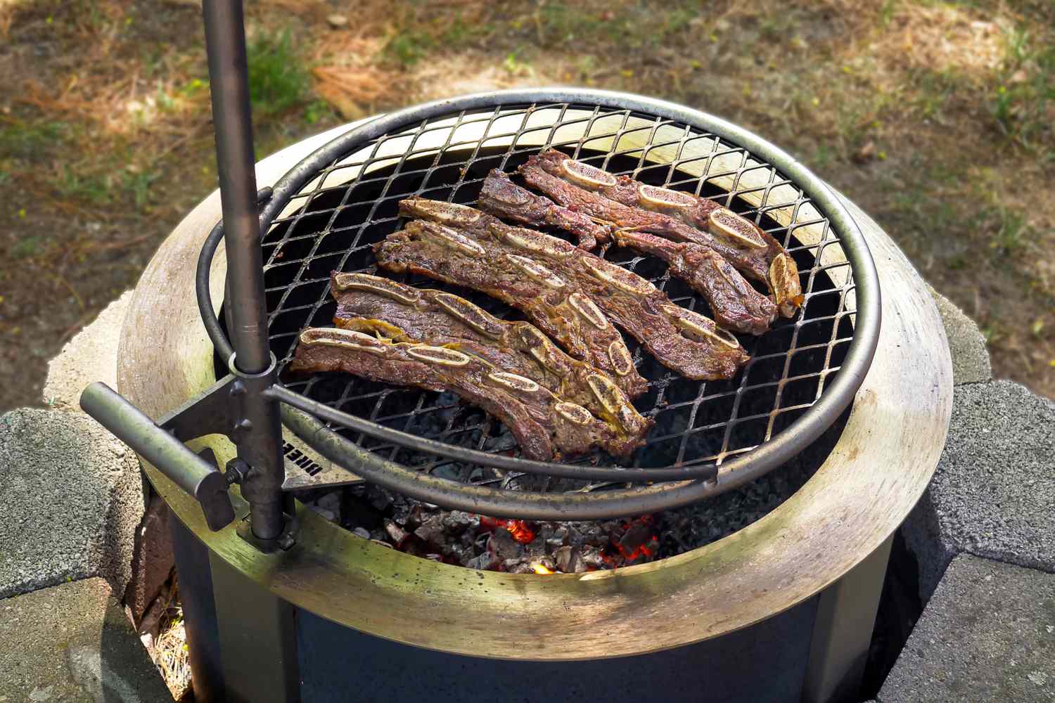 Korean barbecue short ribs grilling over an open flame on a circular outdoor grill