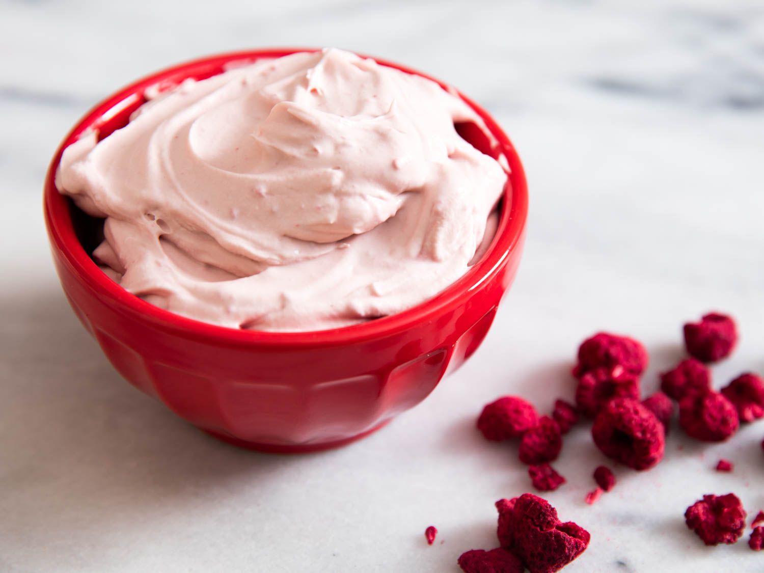 A bowl of raspberry whipped cream with freeze-dried raspberries.
