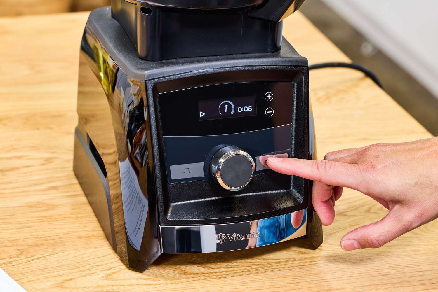 A person presses a button on the front of the Vitamix 12-Cup Food Processor Attachment