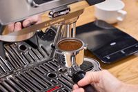 A person adds a portafilter of ground espresso to the De'Longhi La Specialista Touch Espresso Machine