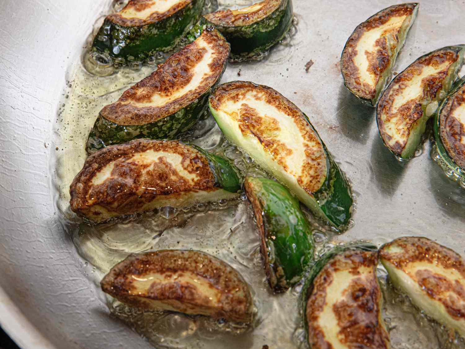Stuffed zucchini rounds frying in a pan