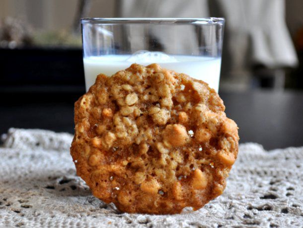 A coconut scotchy cookie, propped up against a glass of milk.