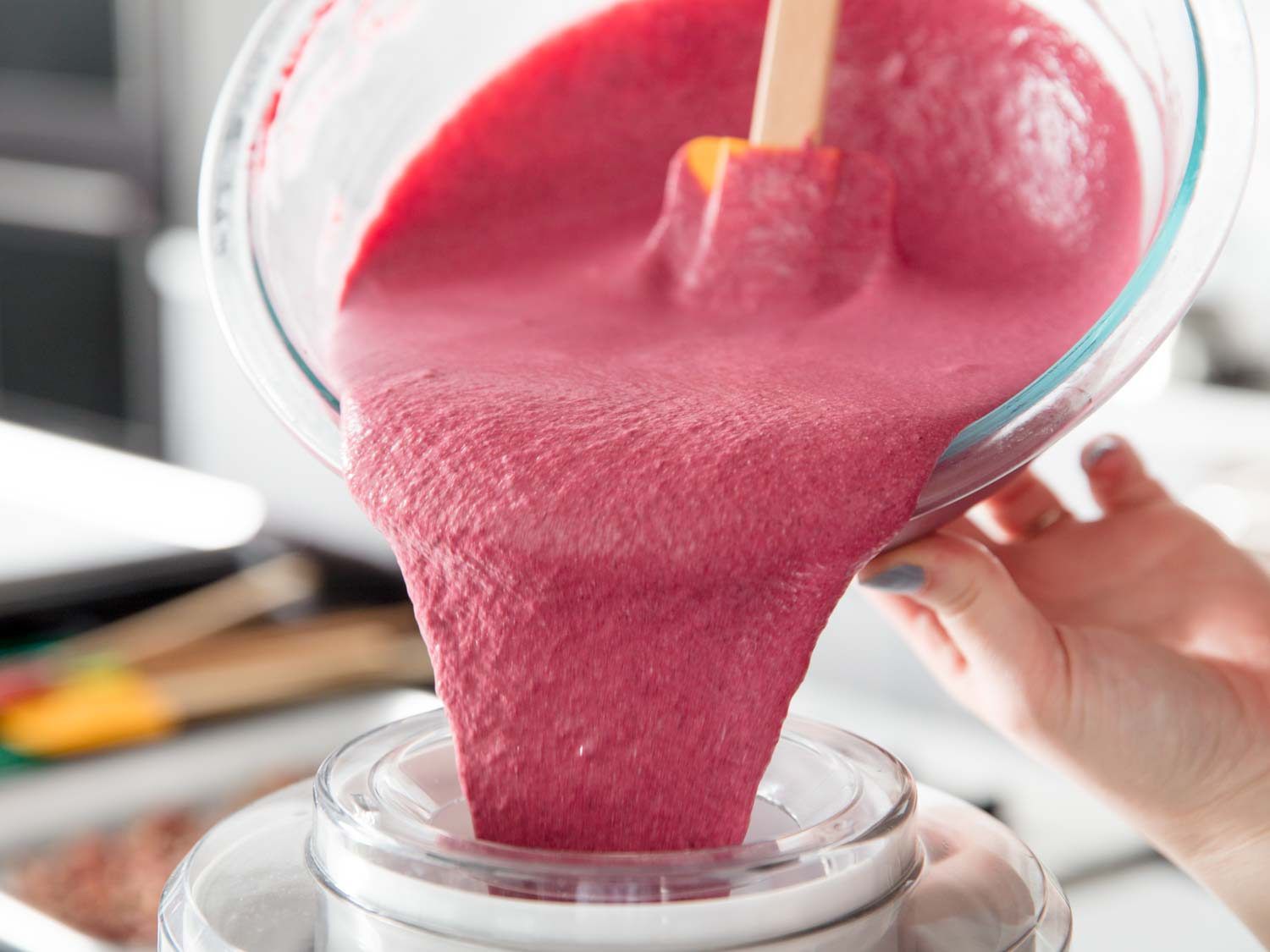 Blackberry ice cream base being poured into an ice cream machine.