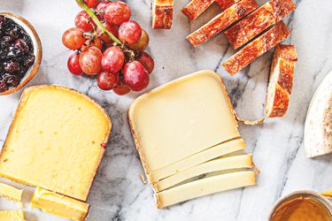 Cheese slices with grapes bread and spreads on a marble surface