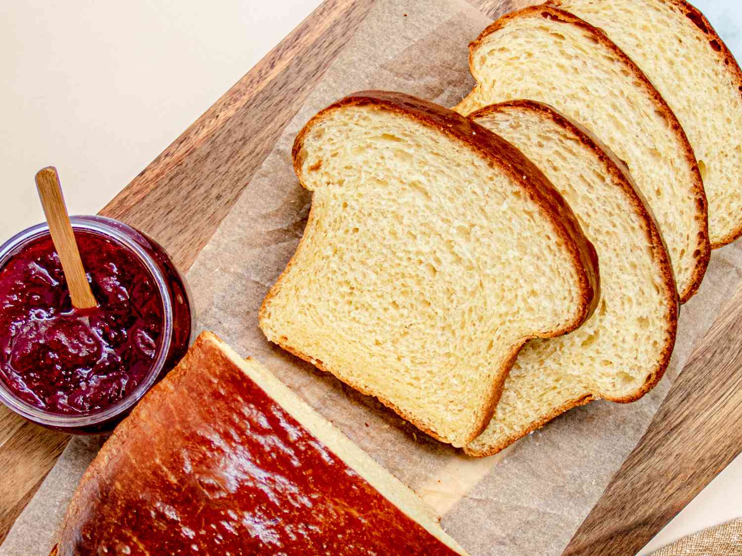 Overhead view of sliced brioche loaf on a cutting board next to jam 
