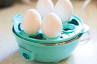 Eggs in their shells sitting in an electric egg cooker