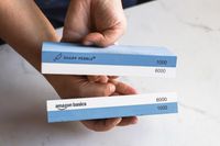 A person comparing two whetstones that look similar