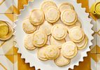 Plate of lemon sugar cookies on a yellow textile on top of yellow and white tiles. 