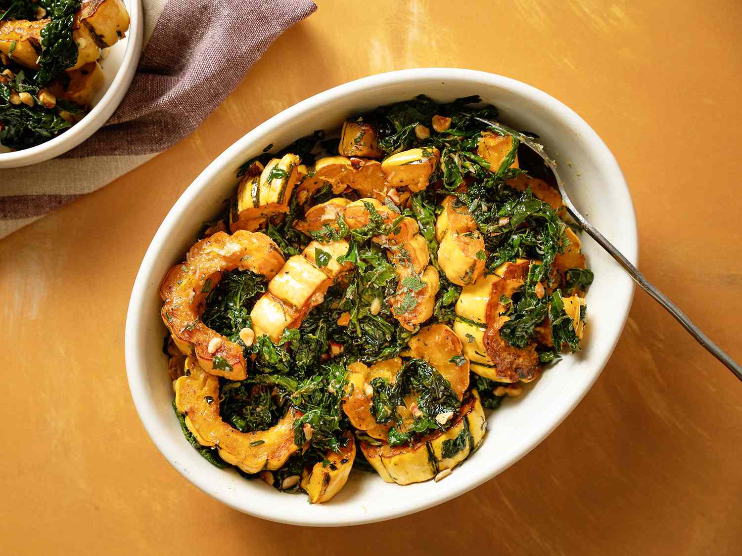 A serving platter of roasted delicata squash and kale salad