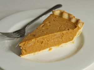 A slice of dairy-free, egg-free coconut pumpkin pie on a white plate with a fork. 