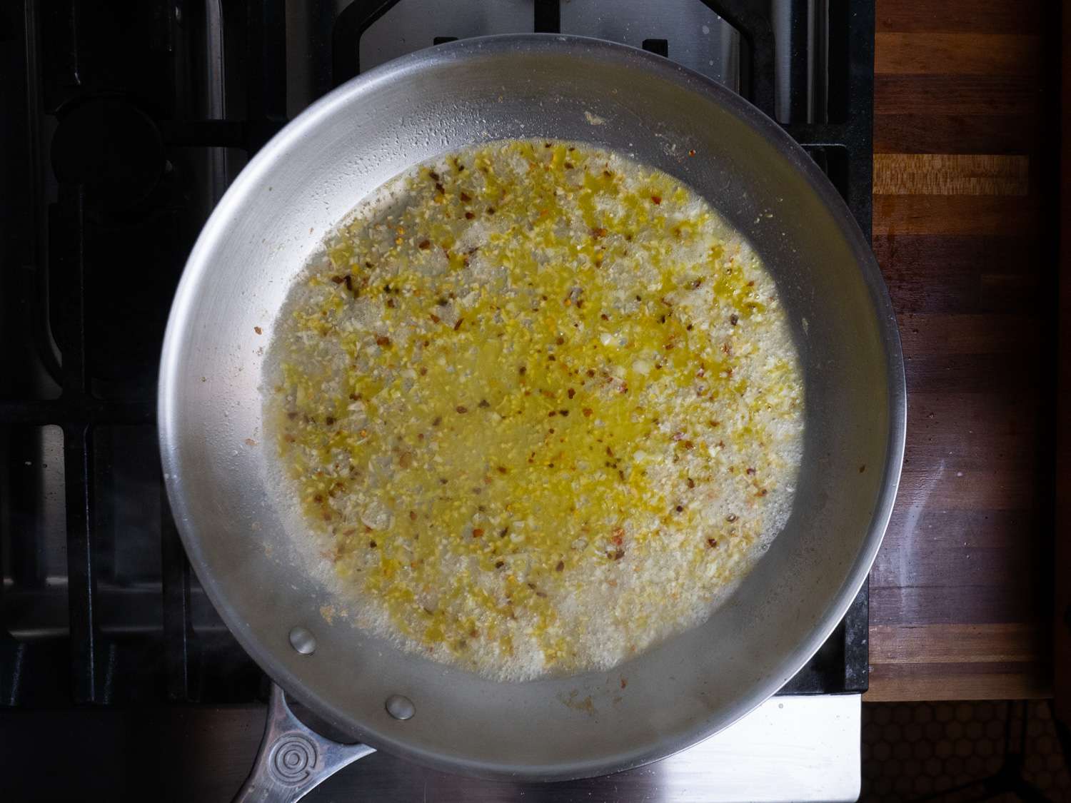 Vermouth added to the garlic, pepper flakes, and oil in a skillet.