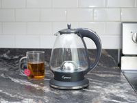 Capresso electric kettle on countertop with tea cup in background