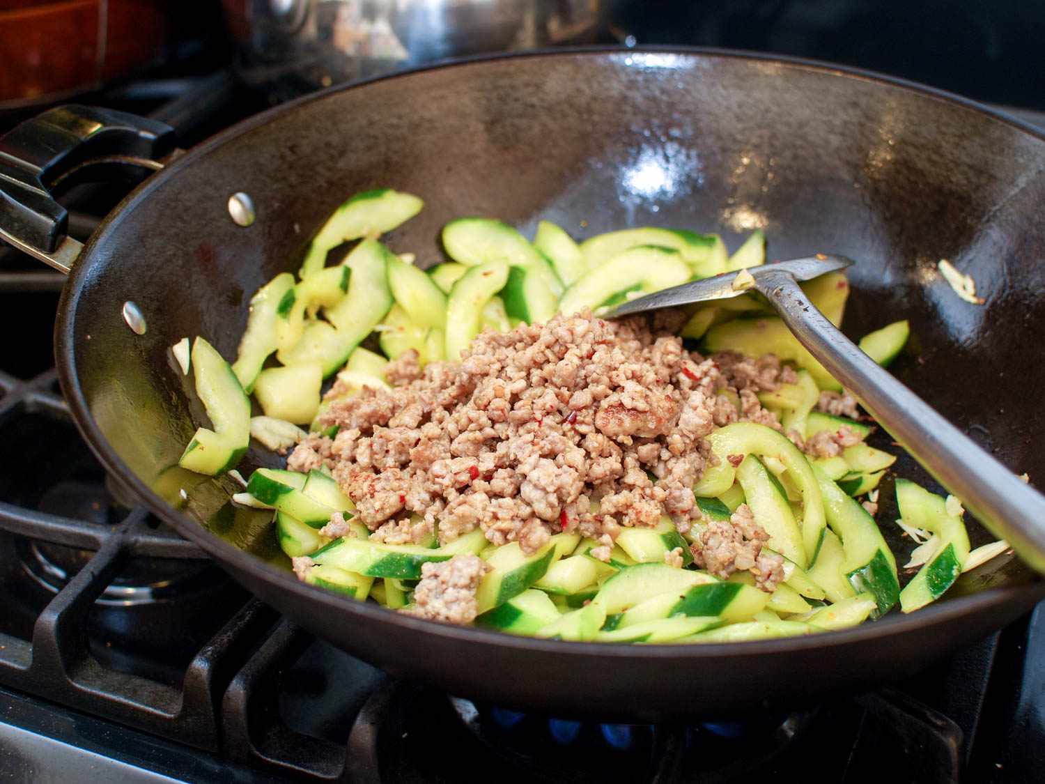 The stir-fried pork has been added back to the wok.