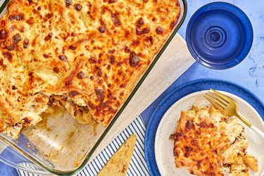 A baked pasta casserole in a glass dish with a portion served on a plate beside it