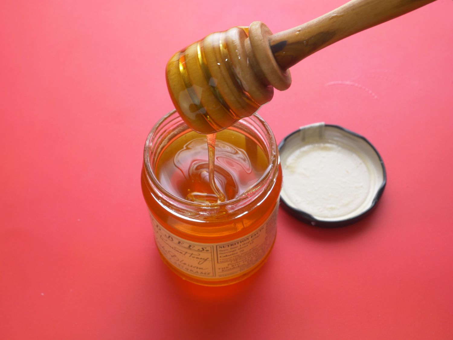a honey dripper dripping honey into a jar