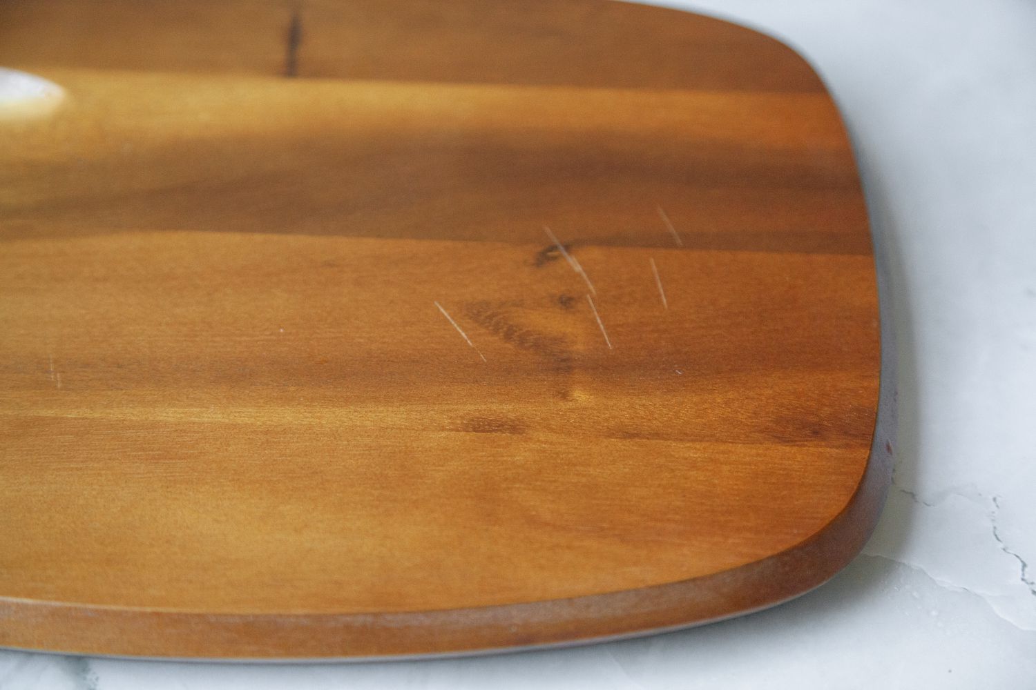 A charcuterie board with several scratches on its surface.