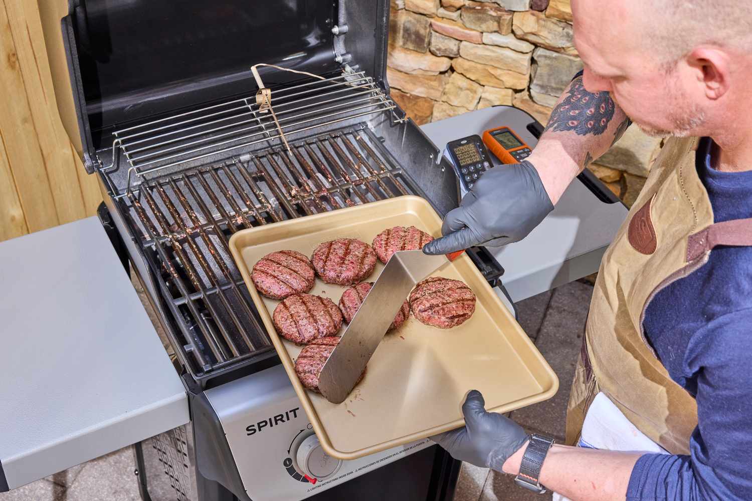A person plating patties on a tray after cooking on the Weber Spirit E-210 Gas Grill