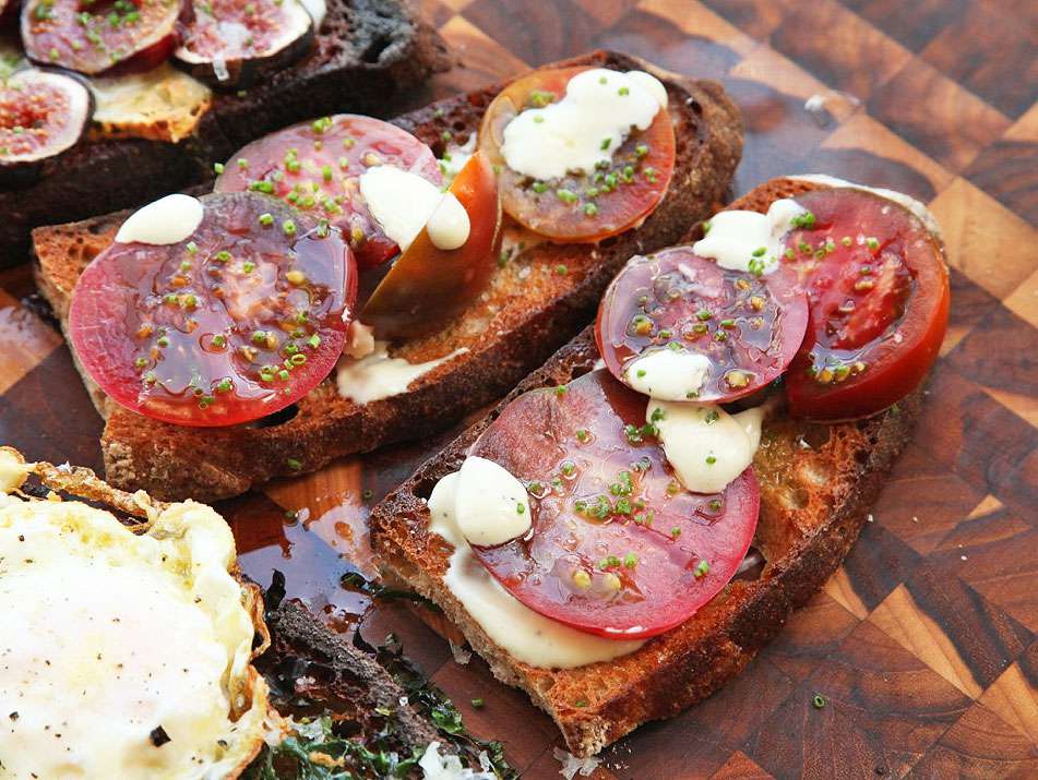 Two Tomato, Alli-oli, and Chive Tartines, assembled on a cutting board.