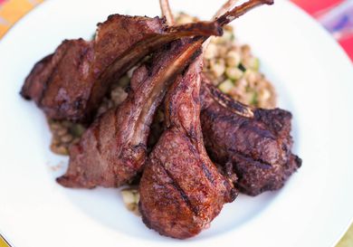 Closeup of grilled berbere-spiced lamb chops, shingled on top of cucumber-lentil salad.
