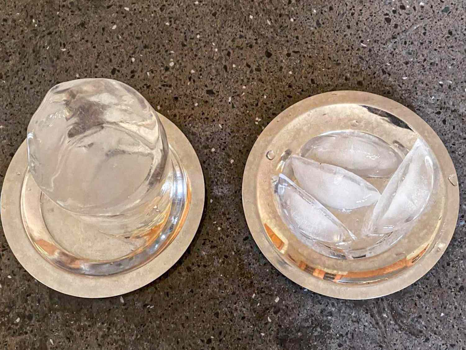 Two servings of clear ice on separate plates one is a sphere and the other is shaped in crescent pieces