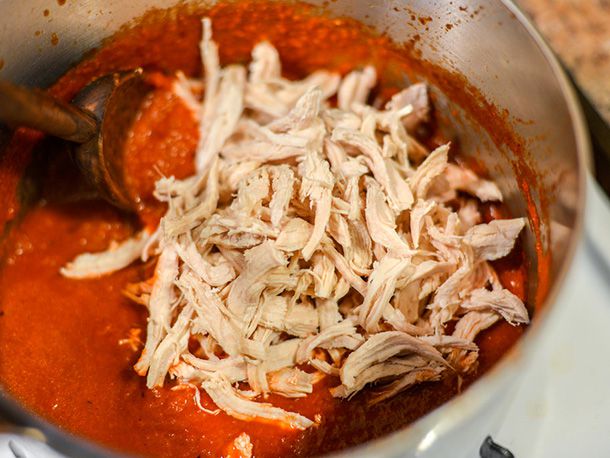 Poached, shredded chicken is added to the simmered and puréed tomato-onion-chipotle mixture and heated through.