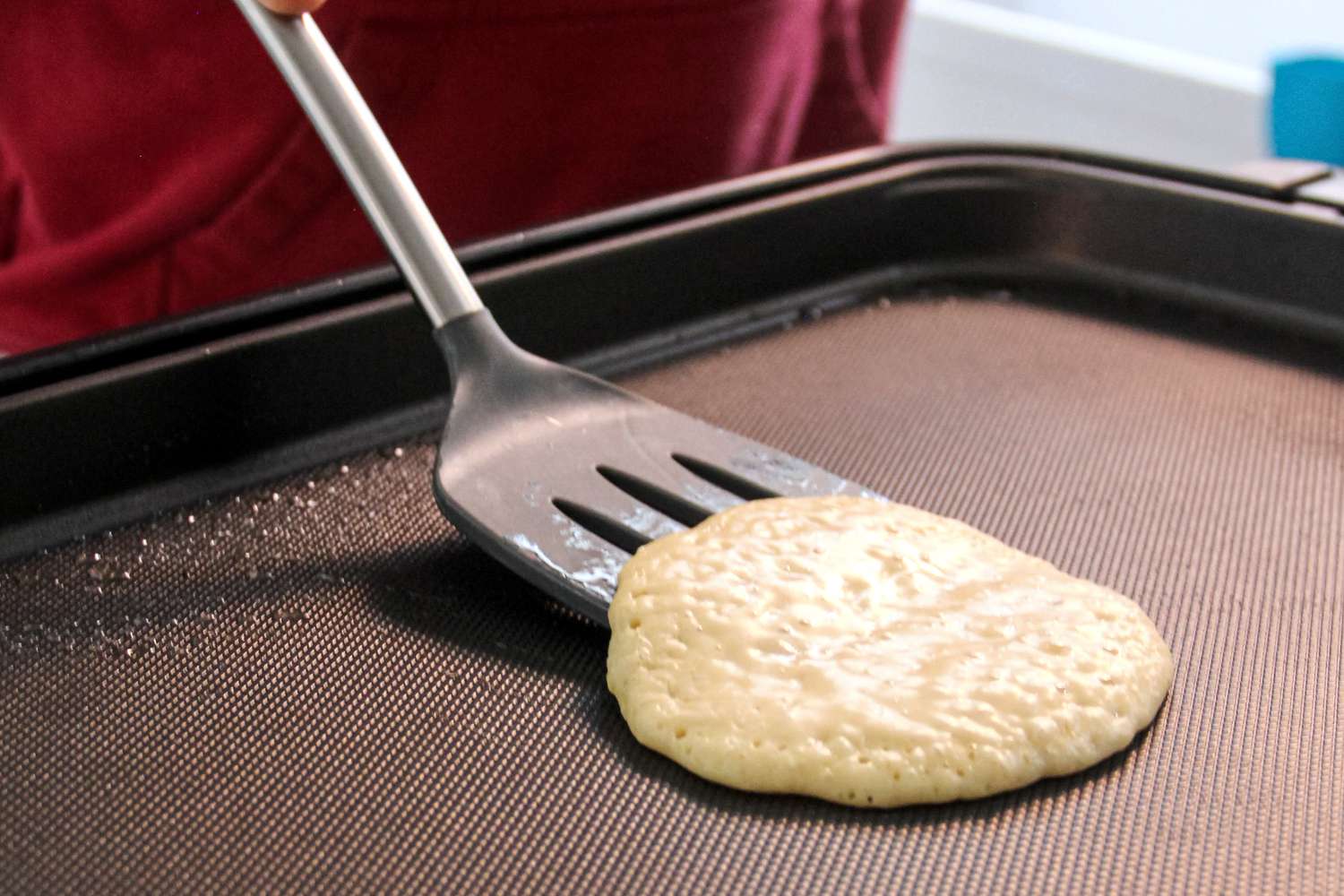 A person using the Tovolo Silicone Slotted Turner to flip a pancake