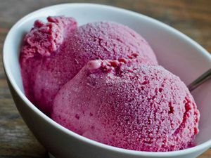Closeup of two scoops of roasted plum, ginger, and honey ice cream, served in a small bowl.