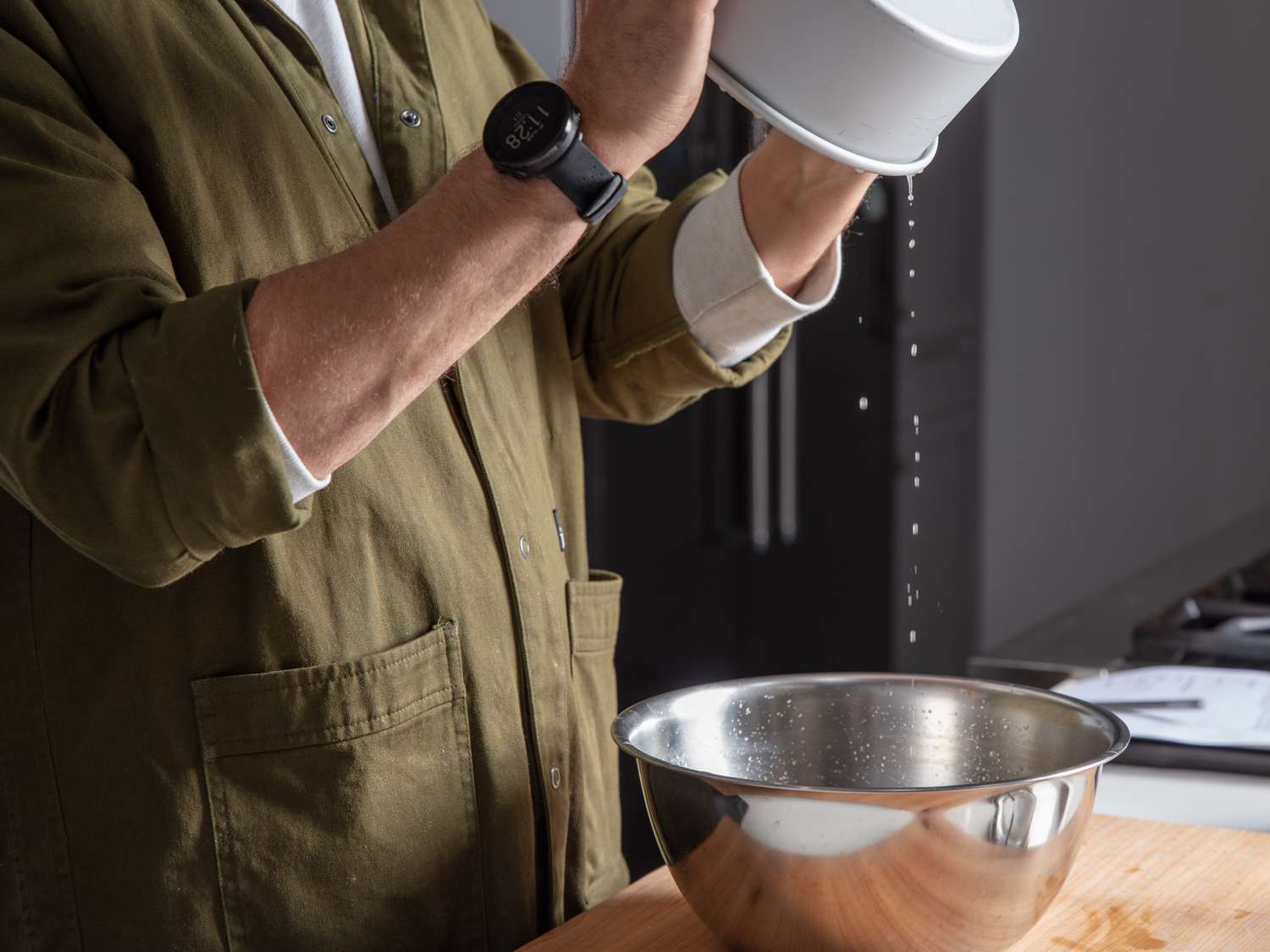 Draining exuded liquid from the raw, salted layered potatoes.