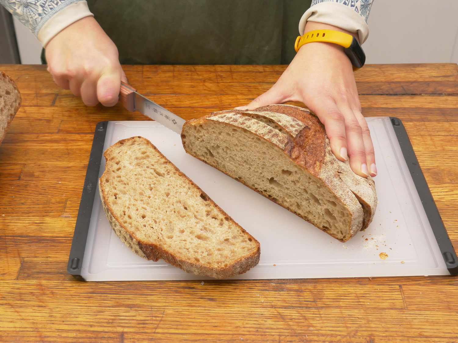 a person slicing bread on the oxo cutting board