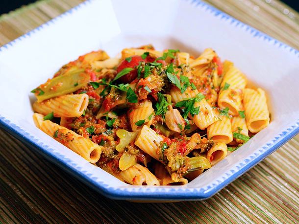 A serving plate of pasta with braised broccoli and tomato. 