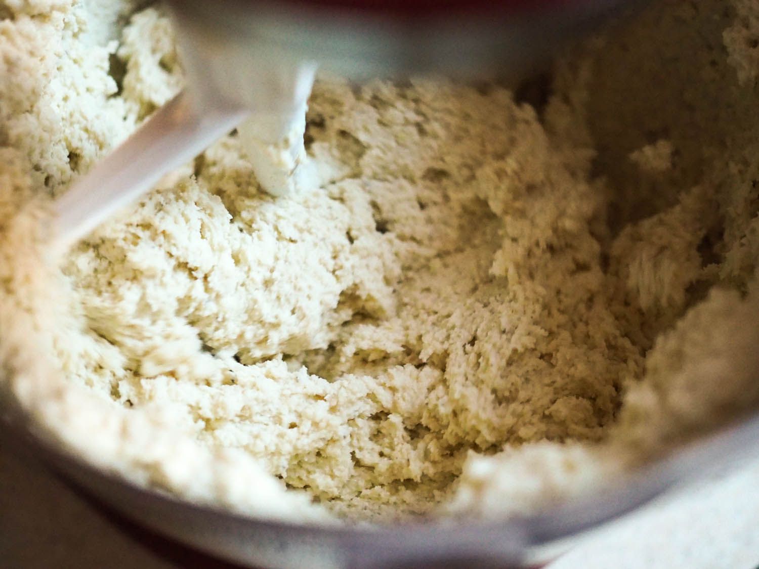 The masa-stock mixture is progressively added to the bowl of the stand mixer.
