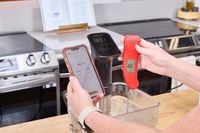 A person takes the temperature of water boiled using the Anova Culinary Precision Cooker Pro